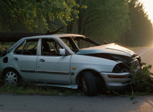 Mașină avariată încurcată într-un copac pe marginea unui drum rural la răsărit