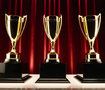 Eleganta ceremonie de premiere: scenă cu lumini sclipitoare, trofee abstracte pe piedestale, atmosferă festivă într-un salon de bal luxos al unui hotel. Iluminare cinematografică, 8k, hiper-realist.